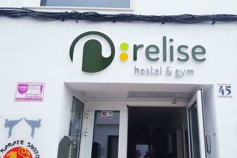 Logo y letrero corpóreo en relieve sobre la entrada del hostal/gym.