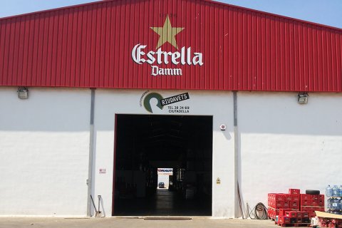 Fachada de la nave industrial de la marca Estrella Damm  con logo corporativo de la misma.