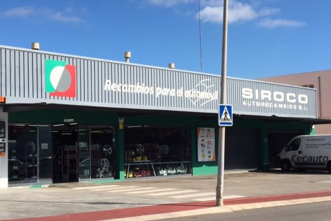 Fachada de la tienda Siroco en Mahón con letrero en relieve monocromático y logo de Cecauto.